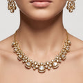 Gold-toned jewelry set featuring a choker necklace and matching drop earrings worn by a model. The jewelry is embellished with clear stones and features a warm gold metal setting.