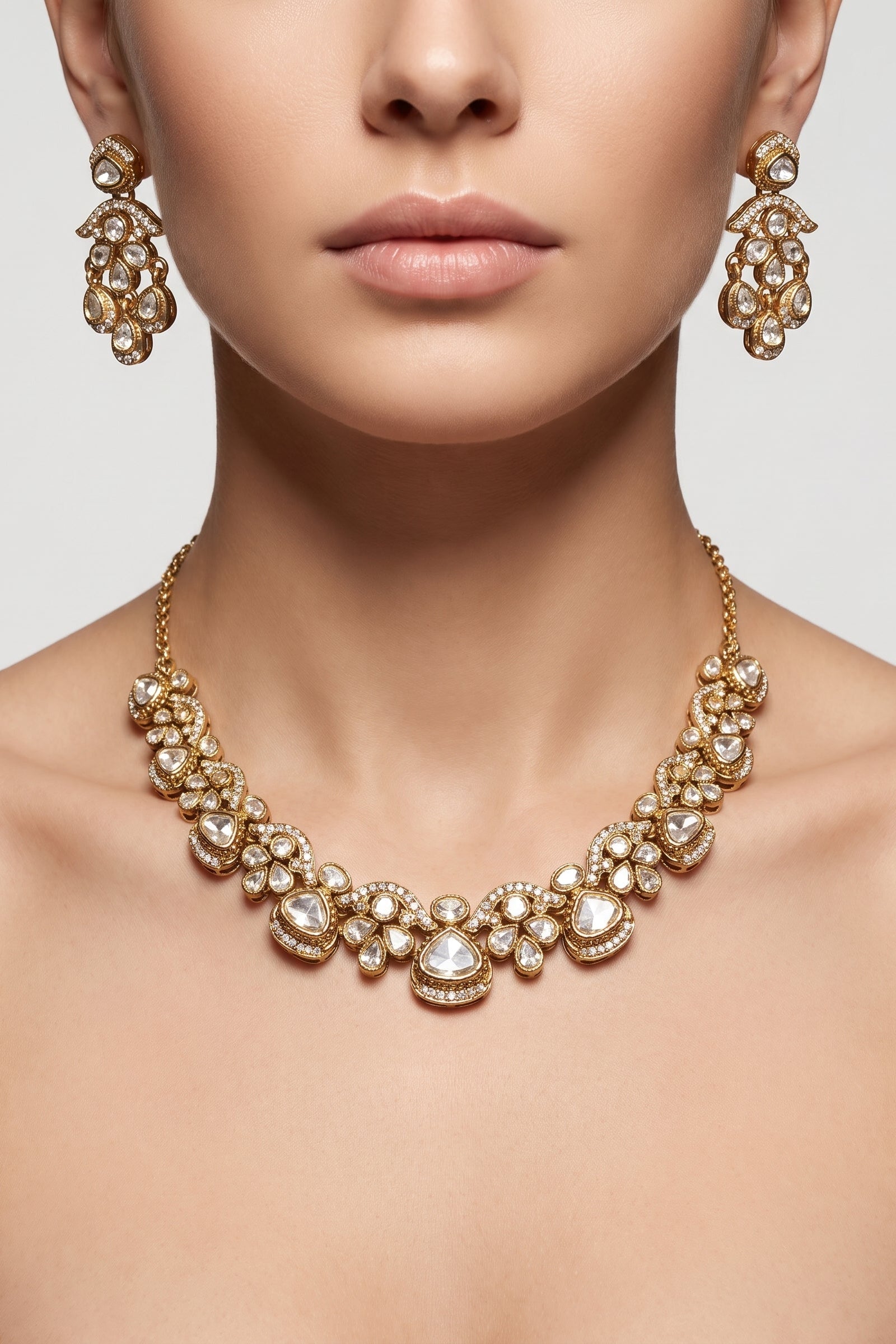 Gold-toned jewelry set featuring a choker necklace and matching drop earrings worn by a model. The jewelry is embellished with clear stones and features a warm gold metal setting.